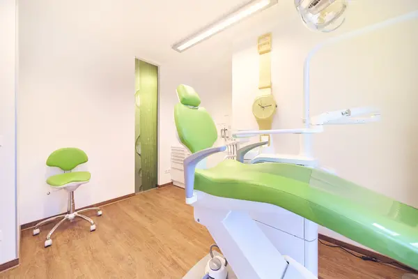 Moderner Zahnarztpraxisraum mit grünem Behandlungsstuhl und heller, freundlicher Atmosphäre.